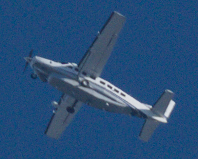 grainy crop of a light aircraft in the sky
